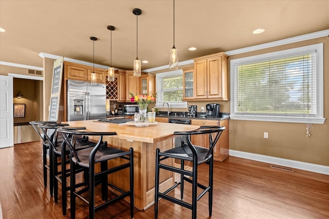 kitchen with wooden counters, stainless steel appliances, crown molding, a kitchen island, and hanging light fixtures