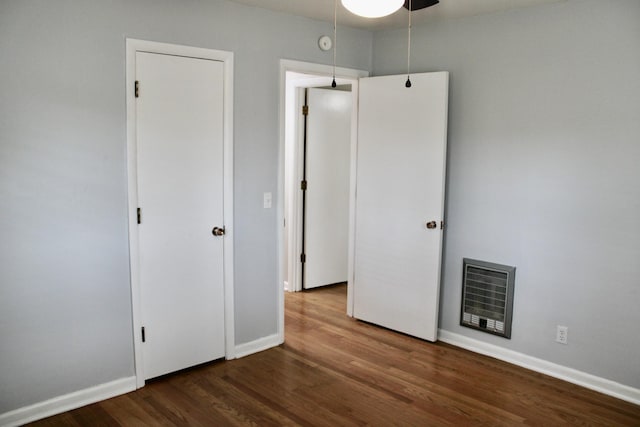 unfurnished bedroom with dark hardwood / wood-style floors, ceiling fan, and heating unit