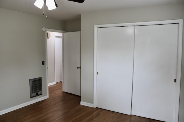 unfurnished bedroom featuring heating unit, ceiling fan, a closet, and dark hardwood / wood-style floors