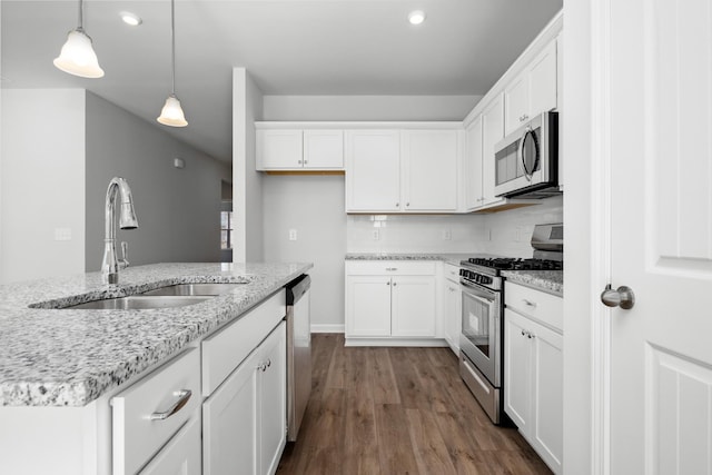 kitchen featuring white cabinets, stainless steel appliances, hanging light fixtures, and sink