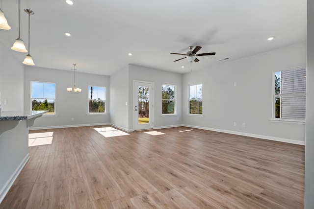 unfurnished living room featuring ceiling fan with notable chandelier and light hardwood / wood-style flooring