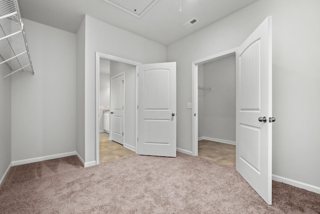 unfurnished bedroom featuring a spacious closet, a closet, and light carpet