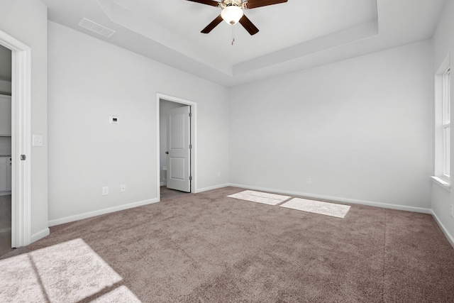 unfurnished bedroom with carpet, ceiling fan, and a raised ceiling