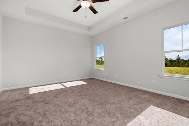 empty room featuring carpet floors, a raised ceiling, and ceiling fan