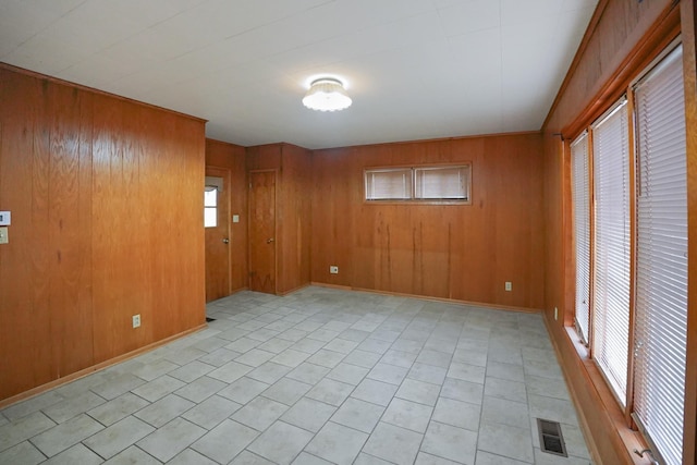 unfurnished room featuring light tile patterned flooring and wood walls