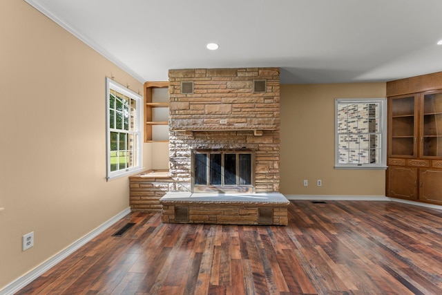 unfurnished living room featuring crown molding, dark hardwood / wood-style flooring, and a fireplace