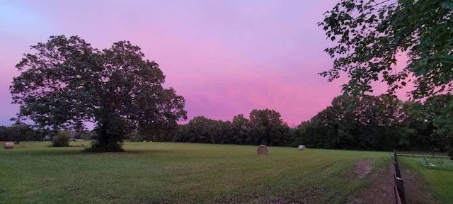 yard at dusk featuring a rural view