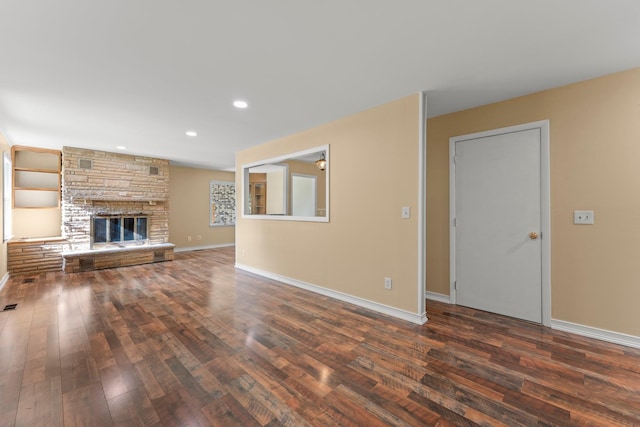 unfurnished living room featuring dark hardwood / wood-style flooring, built in features, and a fireplace