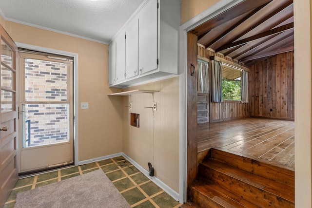 laundry room with cabinets, washer hookup, wood walls, a textured ceiling, and ornamental molding