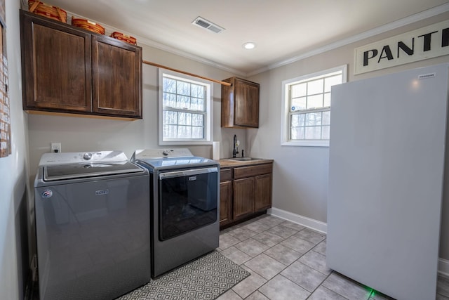 laundry room featuring washer and clothes dryer, cabinets, plenty of natural light, and sink