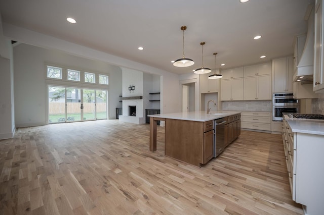 kitchen with white cabinetry, tasteful backsplash, pendant lighting, a center island with sink, and appliances with stainless steel finishes