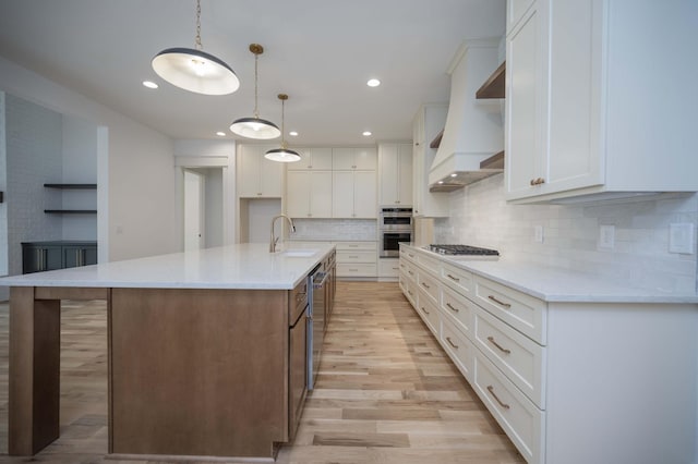 kitchen featuring decorative light fixtures, white cabinetry, and a kitchen island with sink