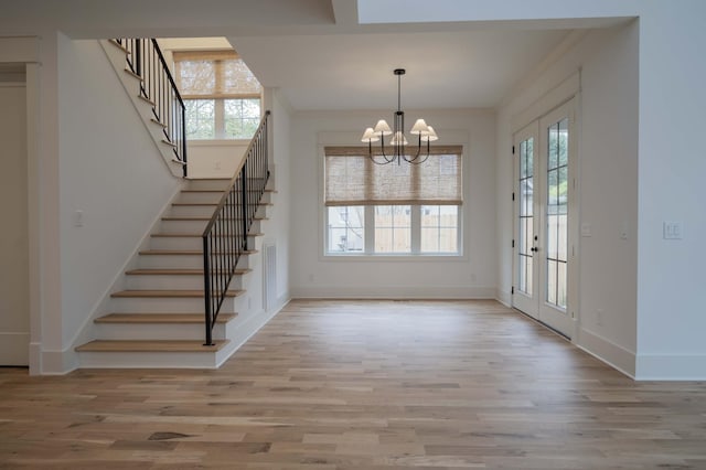 interior space featuring a healthy amount of sunlight, french doors, ornamental molding, and an inviting chandelier