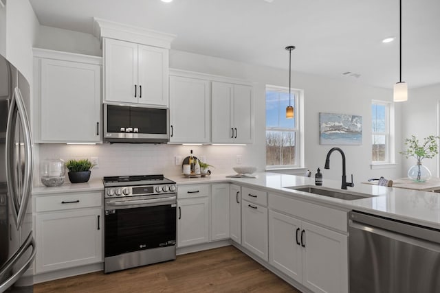 kitchen with sink, stainless steel appliances, dark hardwood / wood-style flooring, decorative light fixtures, and white cabinets