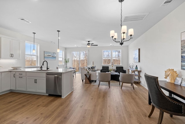 kitchen with dishwasher, sink, hanging light fixtures, white cabinets, and light wood-type flooring