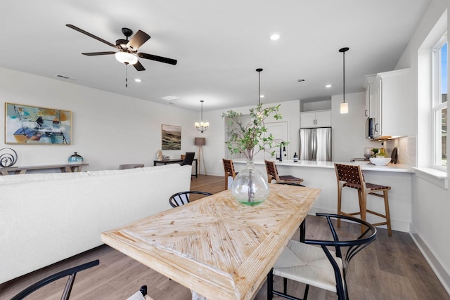 dining area featuring ceiling fan with notable chandelier, a healthy amount of sunlight, and light hardwood / wood-style floors