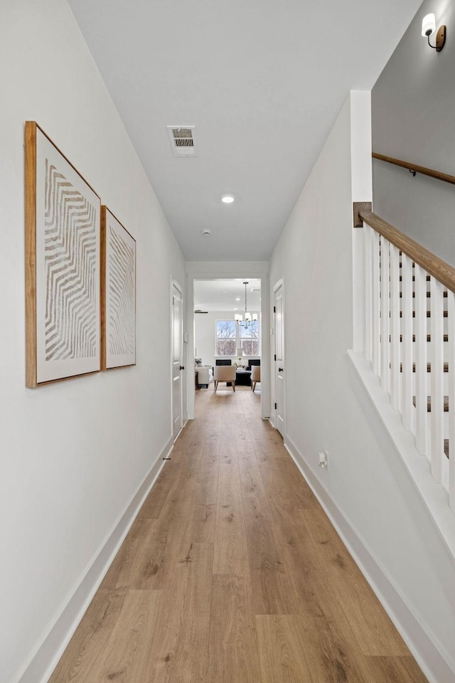 corridor with light hardwood / wood-style flooring and a chandelier