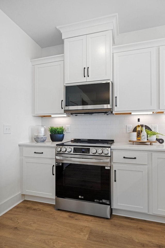 kitchen with white cabinets, backsplash, light wood-type flooring, and stainless steel appliances