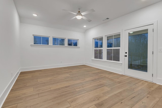 empty room with ceiling fan and light hardwood / wood-style flooring