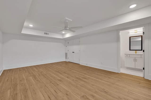 empty room featuring light hardwood / wood-style floors, a raised ceiling, and ceiling fan