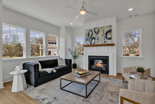 living room with ceiling fan, a fireplace, and light wood-type flooring