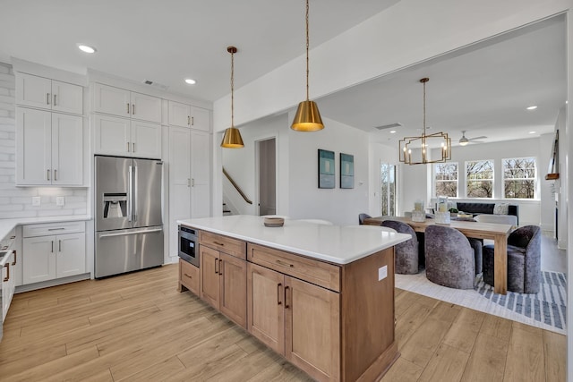 kitchen with a kitchen island, decorative light fixtures, white cabinets, decorative backsplash, and stainless steel appliances