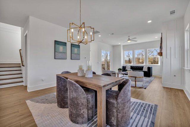 dining space with ceiling fan with notable chandelier and light wood-type flooring