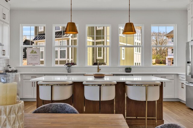 kitchen featuring decorative backsplash, a center island, white cabinets, and a kitchen bar