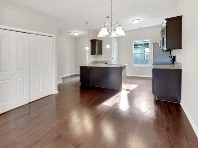 kitchen with a notable chandelier, dark brown cabinets, light stone countertops, and hanging light fixtures