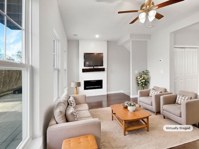 living room with dark hardwood / wood-style flooring, ceiling fan, and a large fireplace