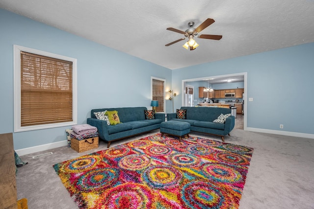 carpeted living room with ceiling fan with notable chandelier and a textured ceiling