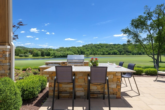 view of patio / terrace with a water view, a grill, a bar, and exterior kitchen