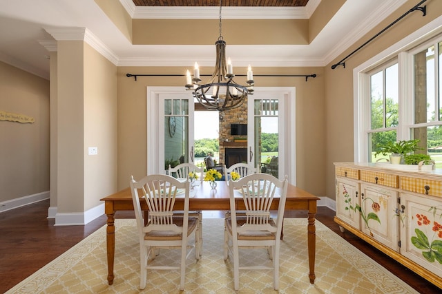 dining area with a tray ceiling, crown molding, dark hardwood / wood-style floors, and an inviting chandelier