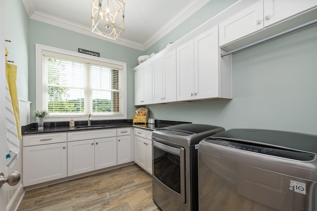 clothes washing area with washer and clothes dryer, cabinets, crown molding, sink, and light hardwood / wood-style floors