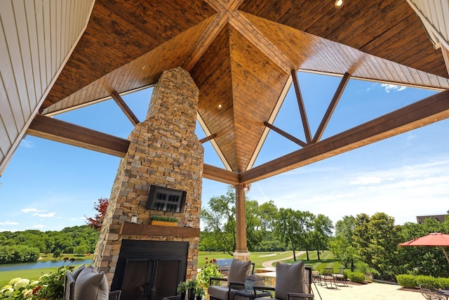 view of patio with an outdoor stone fireplace and a water view