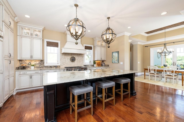 kitchen featuring light stone countertops, a large island, dark hardwood / wood-style flooring, and pendant lighting