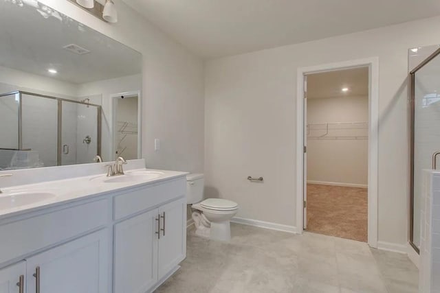 bathroom featuring tile patterned flooring, vanity, a shower with shower door, and toilet