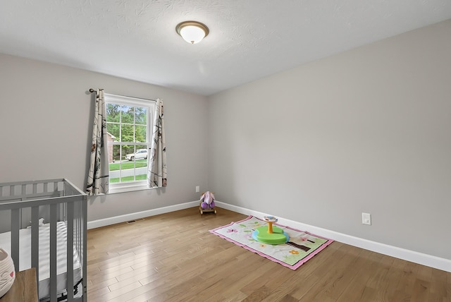 unfurnished bedroom with a nursery area and light wood-type flooring