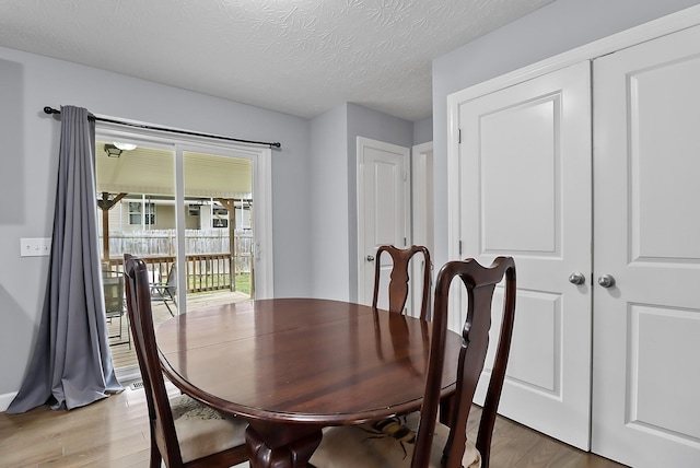 dining area with a textured ceiling and light hardwood / wood-style flooring