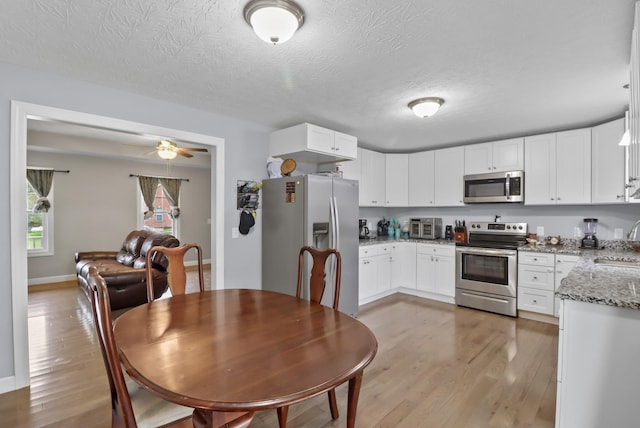 kitchen featuring light stone countertops, sink, light hardwood / wood-style floors, white cabinets, and appliances with stainless steel finishes