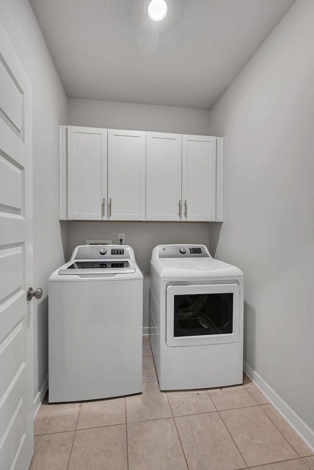 laundry room with cabinets, light tile patterned floors, and washing machine and clothes dryer