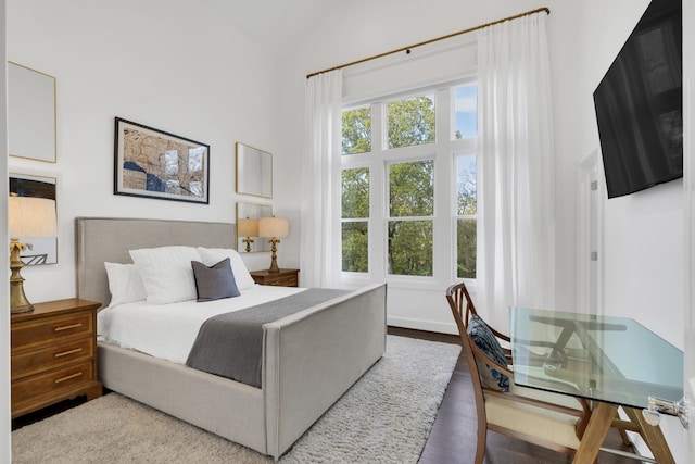 bedroom with hardwood / wood-style floors and a towering ceiling