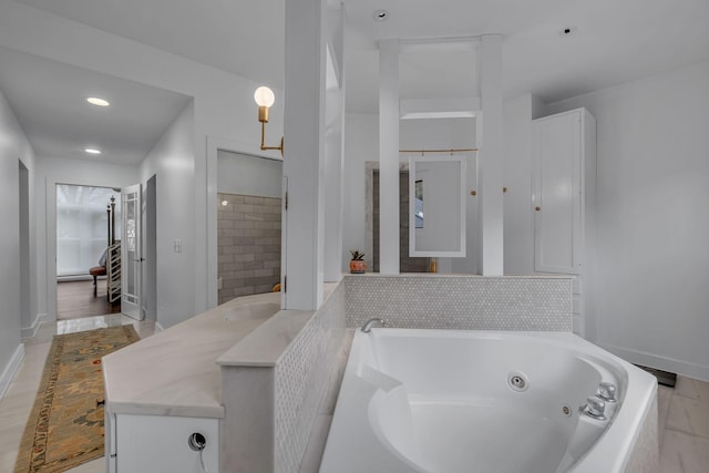 bathroom featuring vanity and a relaxing tiled tub