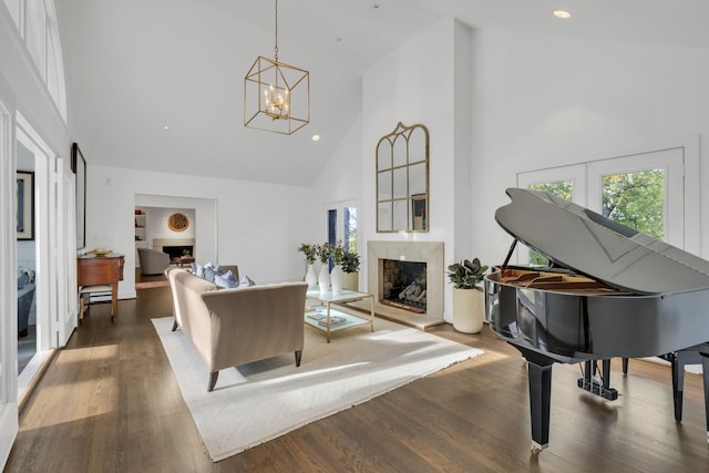 living area featuring hardwood / wood-style flooring, high vaulted ceiling, a high end fireplace, and an inviting chandelier