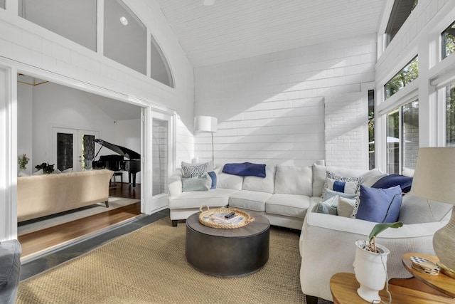 living room featuring french doors, concrete floors, and high vaulted ceiling