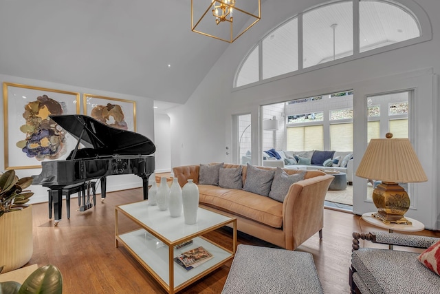 living room featuring wood-type flooring, high vaulted ceiling, and a chandelier