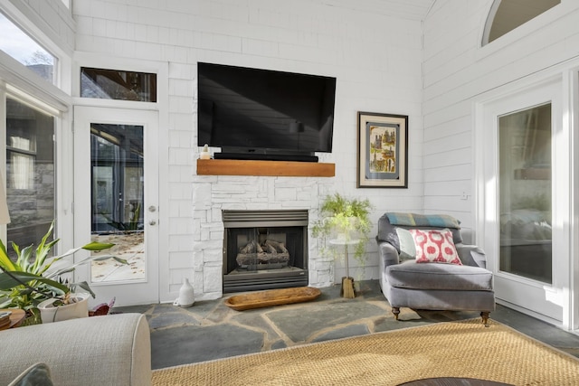 living room with a stone fireplace and a high ceiling