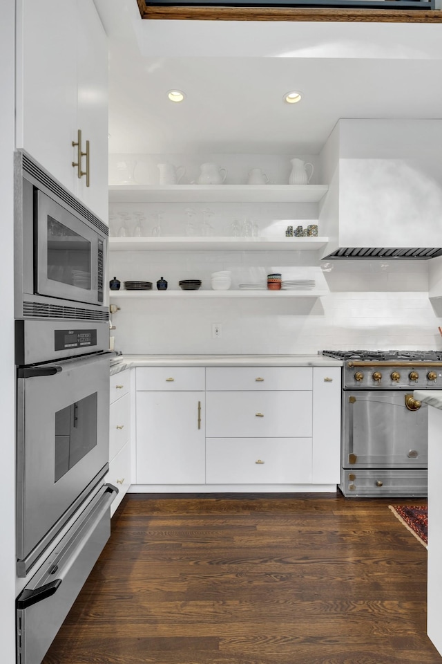 kitchen with white cabinetry, dark hardwood / wood-style flooring, wall chimney range hood, and appliances with stainless steel finishes