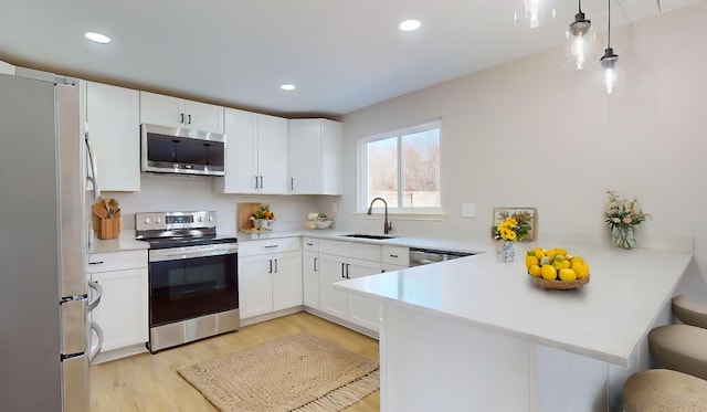 kitchen featuring white cabinetry, kitchen peninsula, stainless steel appliances, and a breakfast bar area