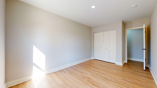 unfurnished bedroom with light hardwood / wood-style flooring and a closet